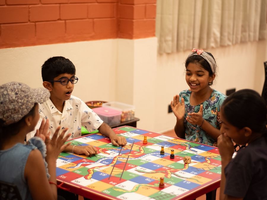 a group of kids playing a board game inside the game room at Ibex River Resort, Pollachi