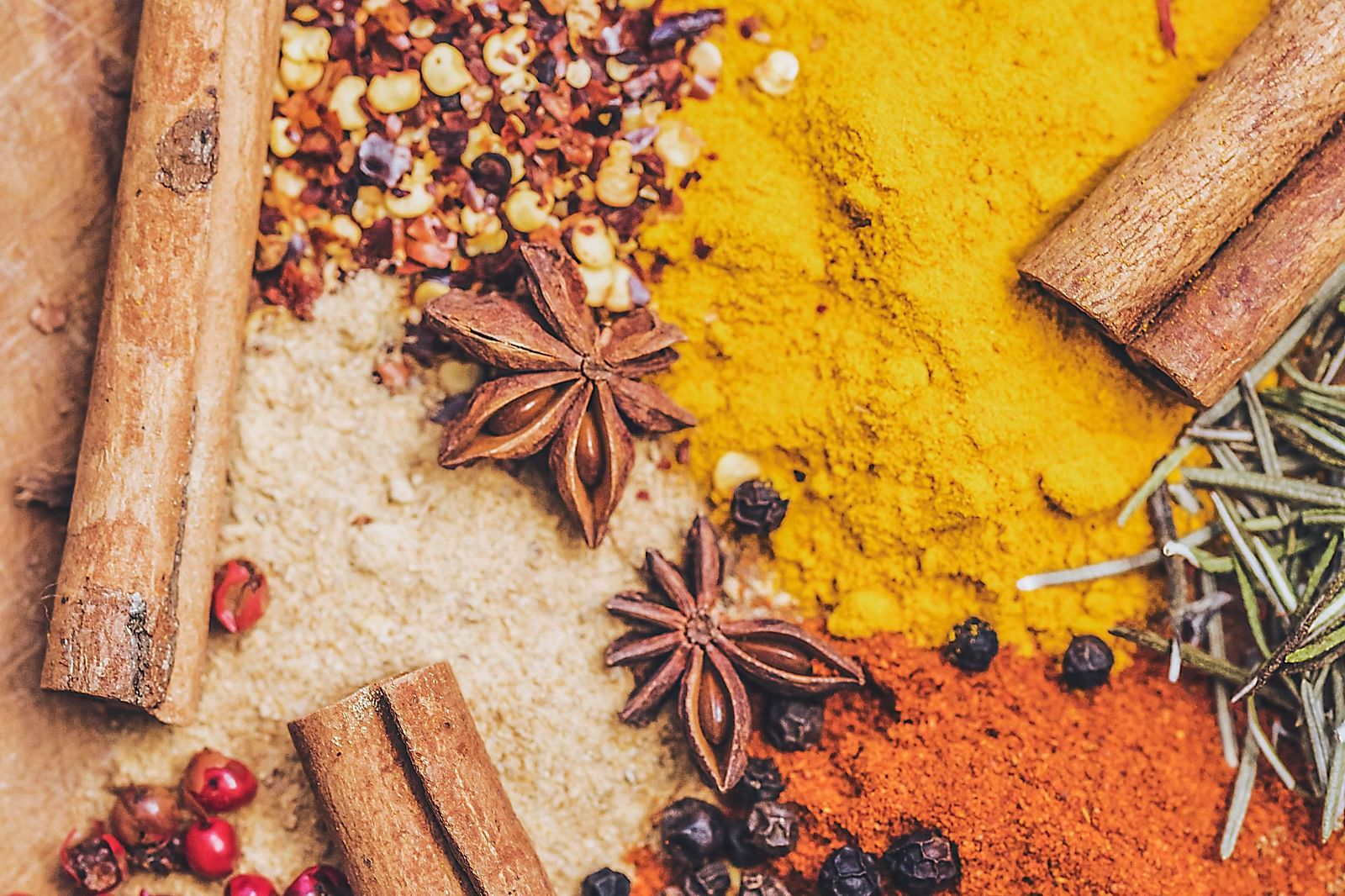An array of vibrant spices and herbs artfully arranged on a wooden surface