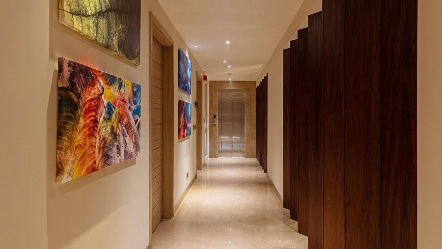A well-lit pathway area at Hotel Saket 27, New Delhi, with artwork frames on the wall and polished floor