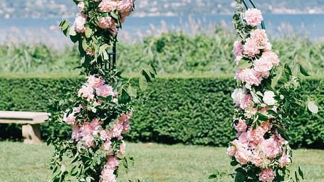 Floral arch with pink blooms against a mountain backdrop. | Vistar Resort, Bengaluru