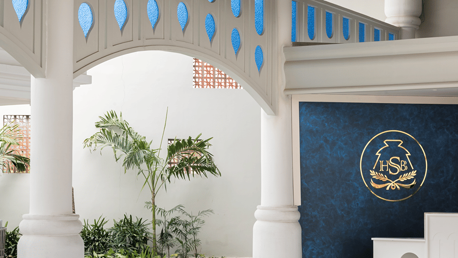 An entrance lobby area at Hotel Sonar Bangla, Mayapur, featuring marble flooring, decorative pillars, and brass decorative bowls.