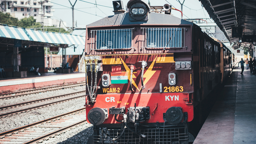 A red and brown train stopped at a covered railway platform