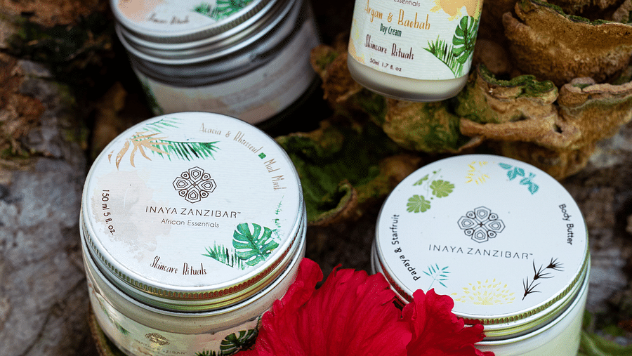 A collection of organic spa products arranged on natural elements, complemented by a vibrant red hibiscus flower at Shooting Star Boutique Hotel