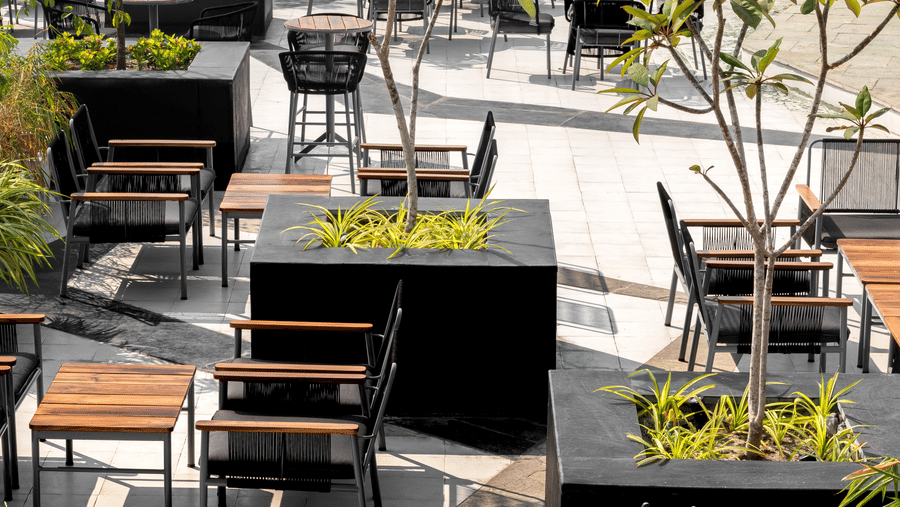 View of outdoor terrace, filled with tables, chairs, and numerous planter boxes with foliage at Hotel Sonar Bangla, Taki.