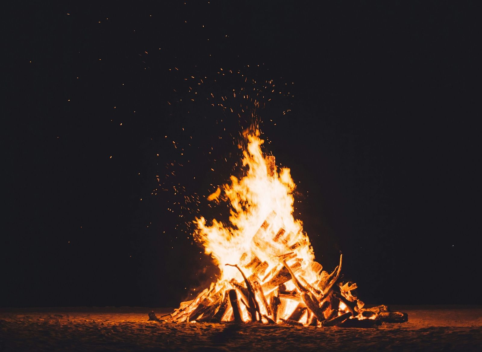 A bonfire burning at night against a black background,
