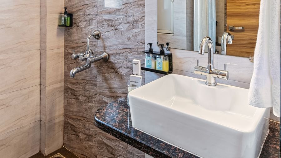 Contemporary bathroom with sleek tile work, a glass-enclosed shower, a large mirror, and a modern sink setup at Mayur Retreat.