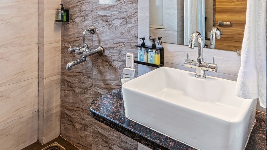 Contemporary bathroom with sleek tile work, a glass-enclosed shower, a large mirror, and a modern sink setup at Mayur Retreat.