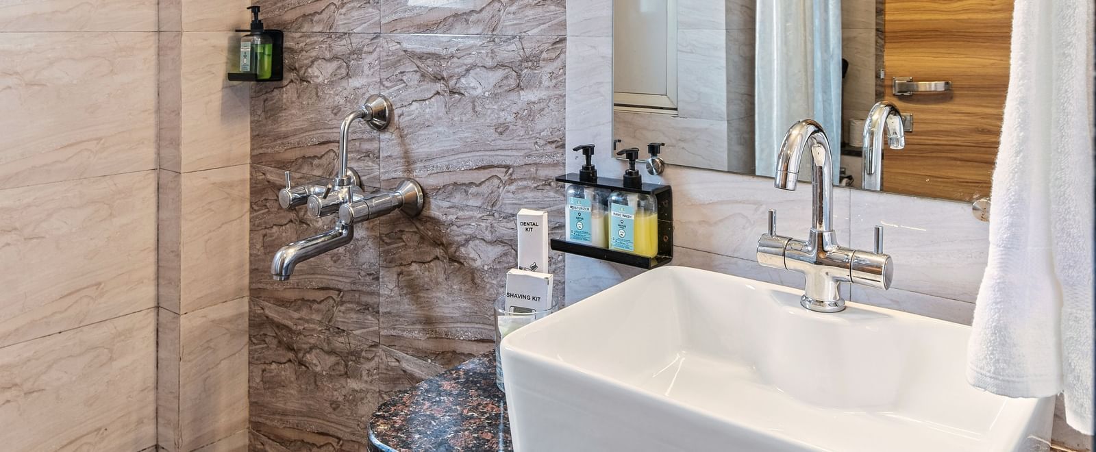 Contemporary bathroom with sleek tile work, a glass-enclosed shower, a large mirror, and a modern sink setup at Mayur Retreat.