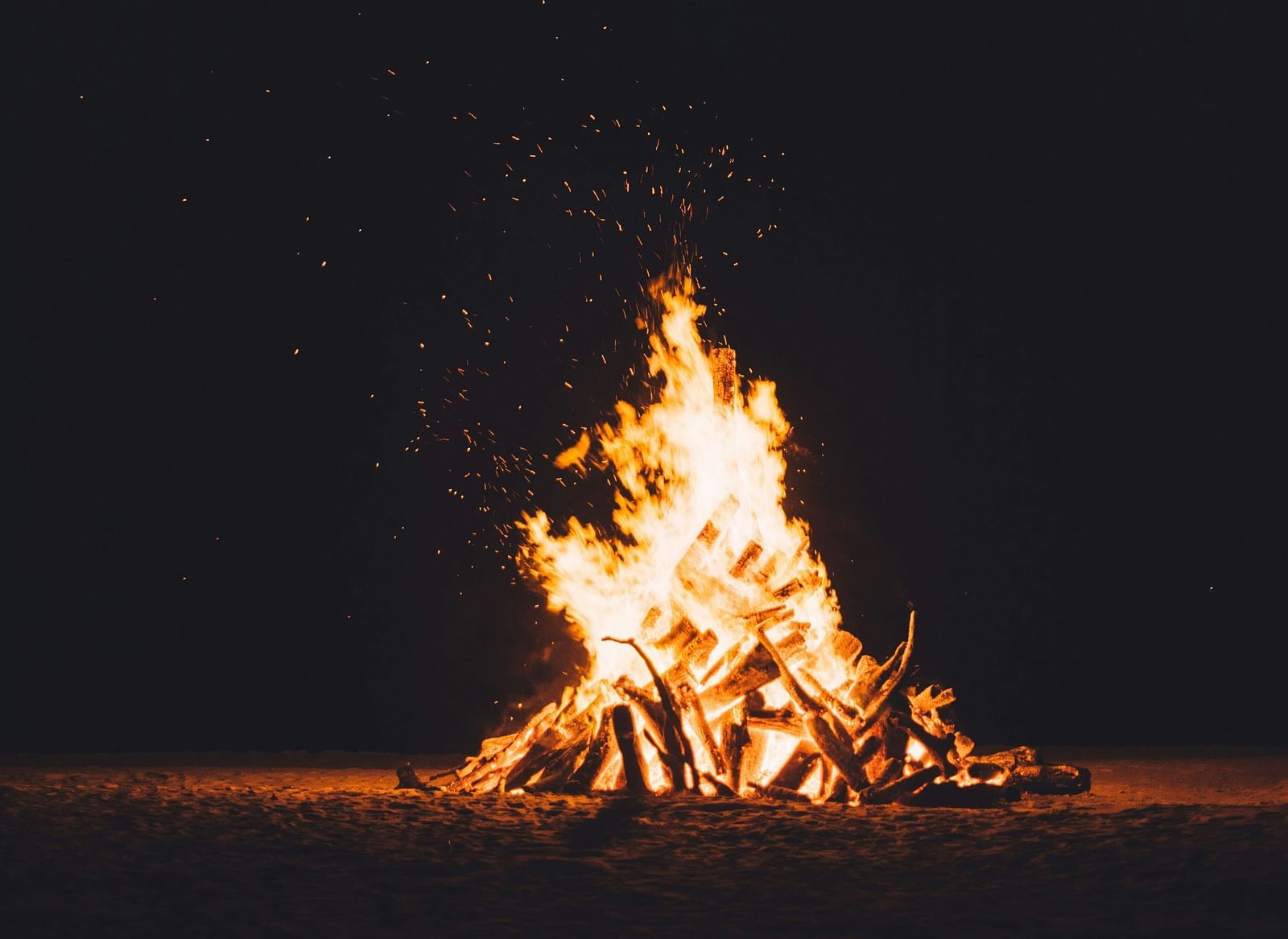 A bonfire burning at night against a black background,