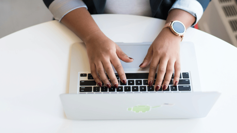 An aerial shot of a woman dressed in formals typing into her laptop.