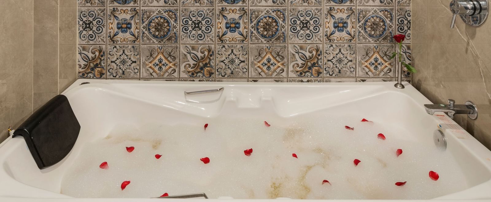 Jacuzzi tub setup at Emerald Retreat, Tungarli with elegant wall tiling and a small window.