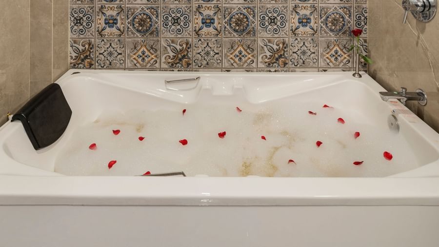 Jacuzzi tub setup at Emerald Retreat, Tungarli with elegant wall tiling and a small window.