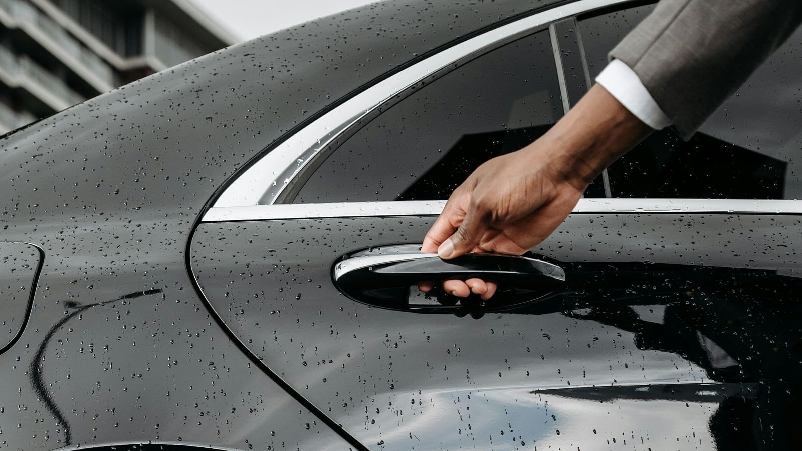 A concierge opening the door to a black car