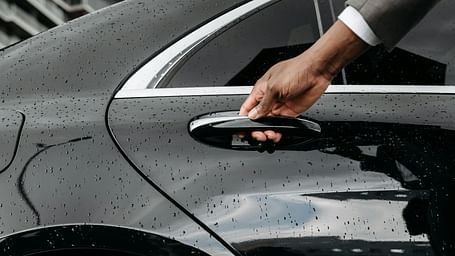 A concierge opening the door to a black car