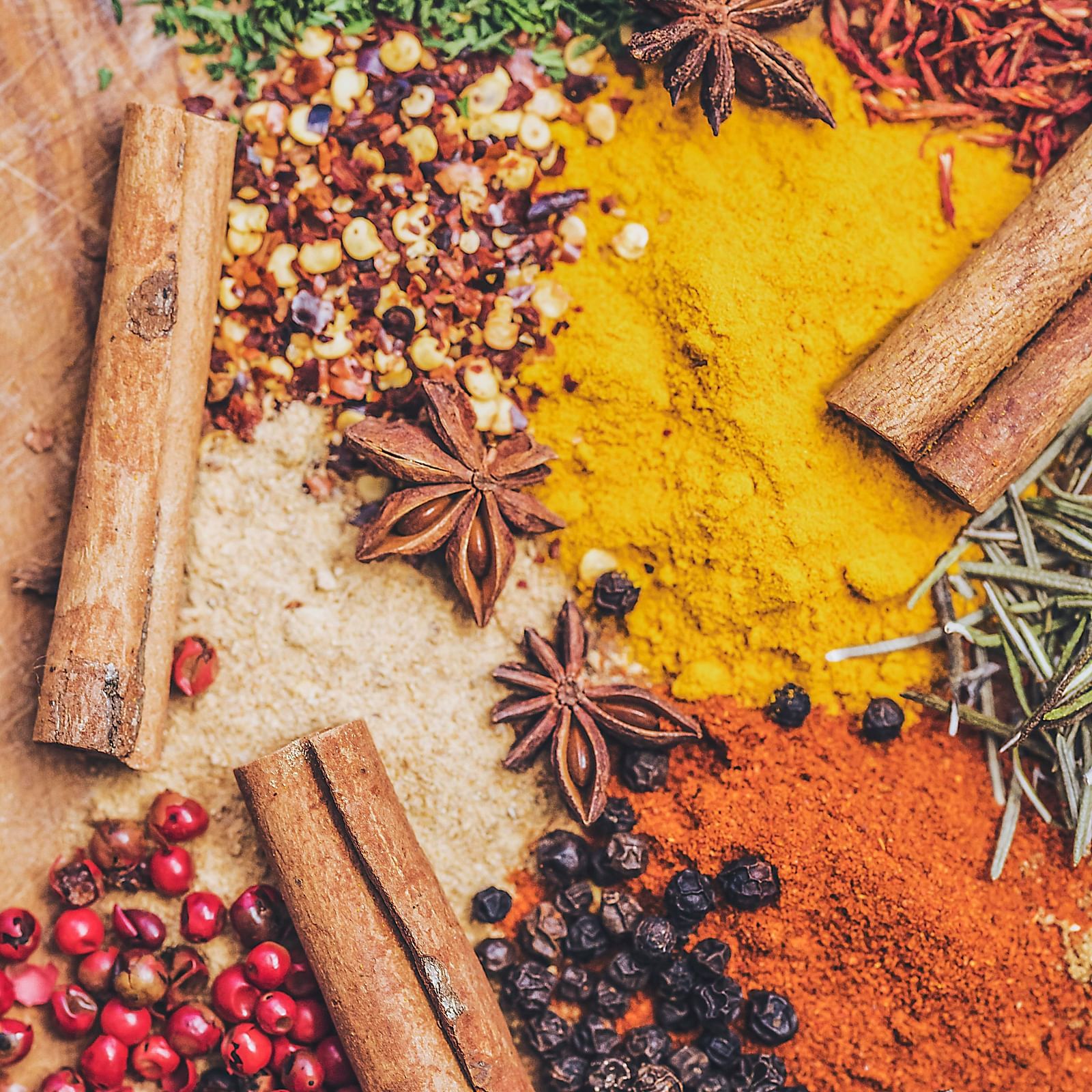 An array of vibrant spices and herbs artfully arranged on a wooden surface