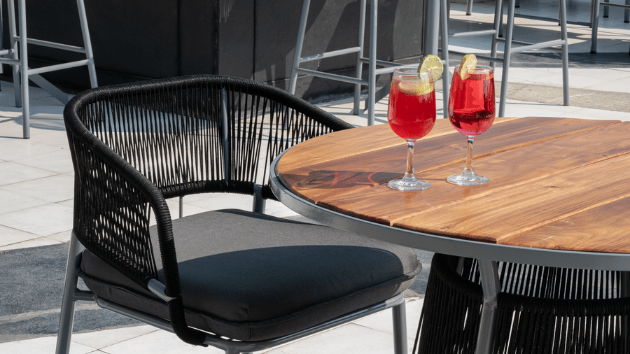 Close up of a wooden table and wicker chairs on a sunny rooftop terrace at Hotel Sonar Bangla, Taki.