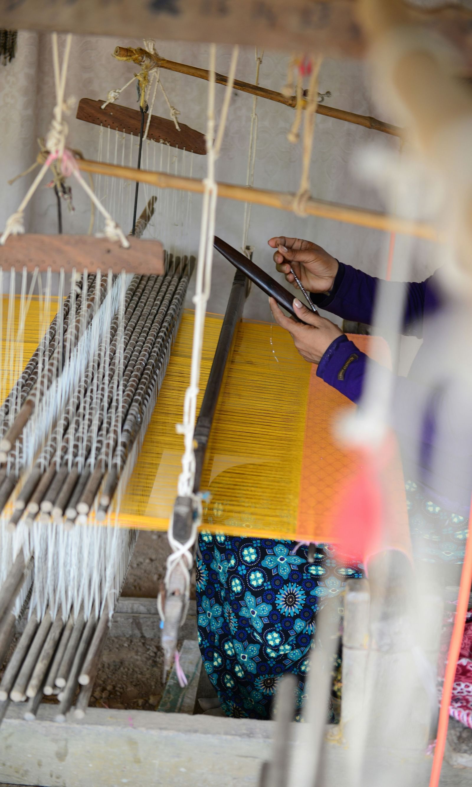 An image of a woman weaving a saree