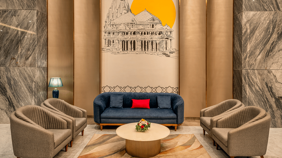 Lobby corner with a plush blue sofa and decorative wall art at Lords Inn Somnath, offering a relaxing and elegant seating space.