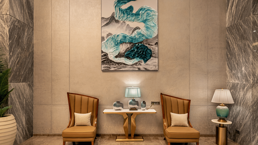 Lobby seating nook with elegant wall artwork and wooden chairs at Lords Inn Somnath, creating a stylish and inviting corner space.