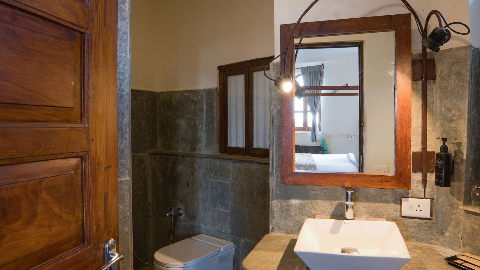 Elegant bathroom with a wooden door, modern sink, and ambient lighting | Mango Hill, Yercaud