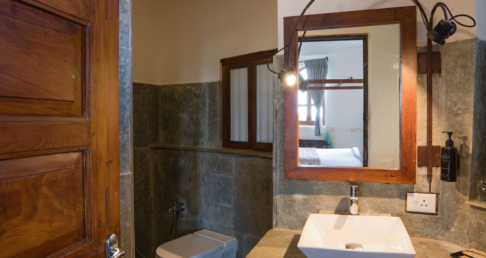 Elegant bathroom with a wooden door, modern sink, and ambient lighting | Mango Hill, Yercaud