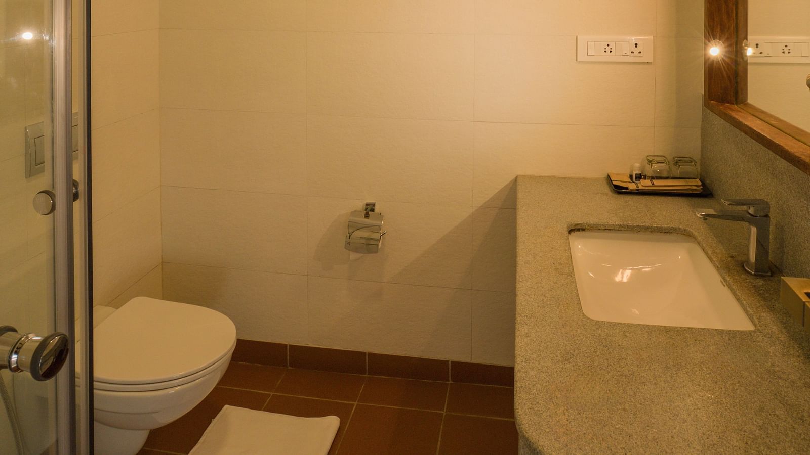 Modern bathroom featuring a glass-enclosed shower, a sleek countertop with a sink, and a well-lit vanity area. | Mango Hill, Yercaud