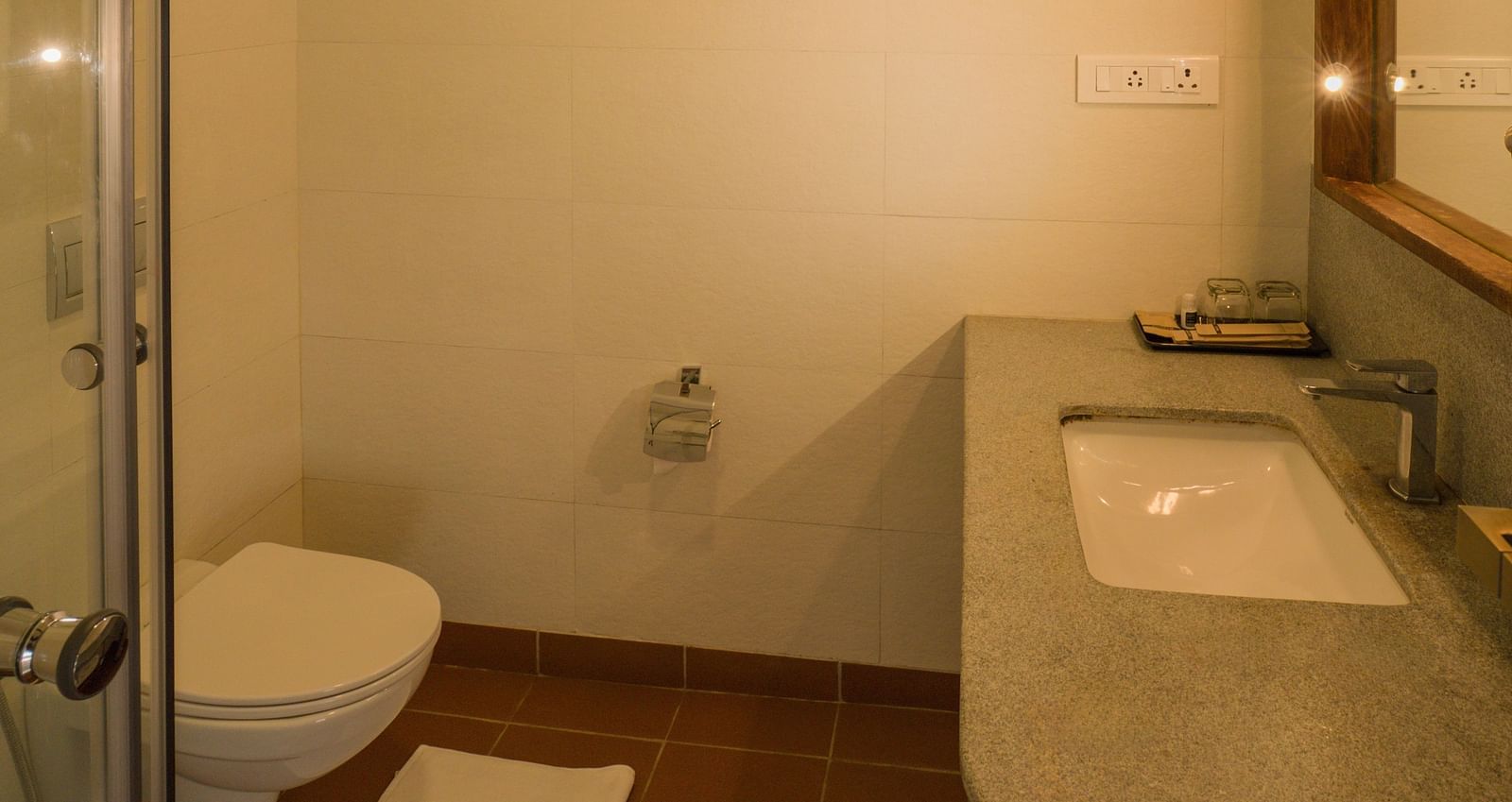 Modern bathroom featuring a glass-enclosed shower, a sleek countertop with a sink, and a well-lit vanity area. | Mango Hill, Yercaud