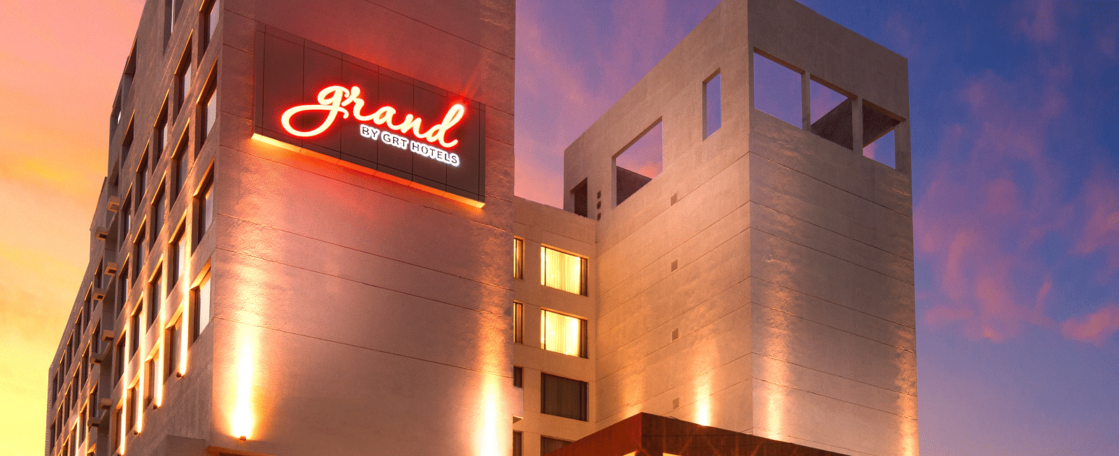 Facade image of Grand Vijayawada by GRT Hotels at dusk with warm golden lighting.