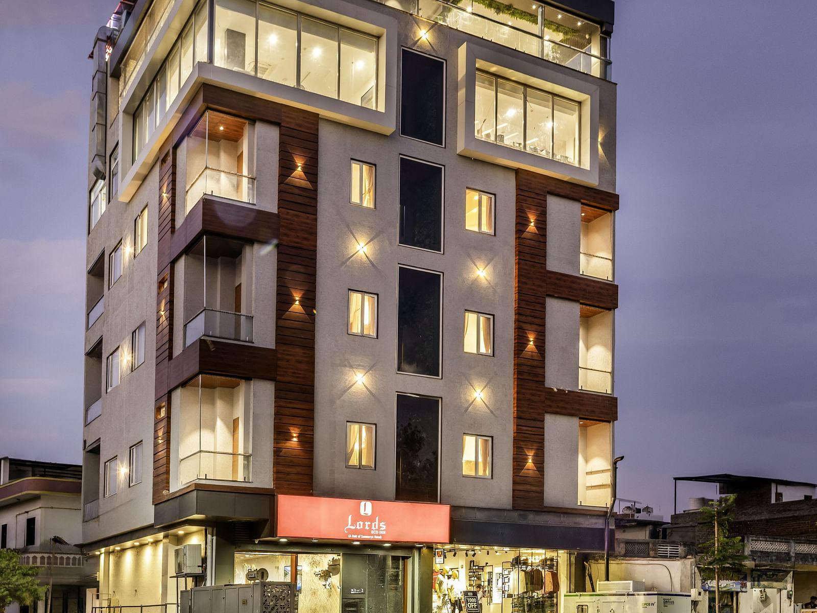 A Luxury  Lords Hotels& Resorts building lit up at dusk, standing tall with modern architecture and a welcoming area near the road