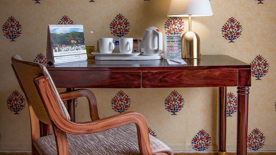 The Table with a calendar, a writing pad and a lamp and a chair at one of the tent suites in Pushkar 