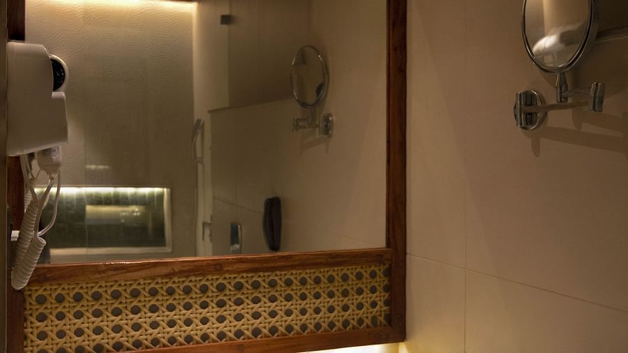 Image of bathroom of Coral Sapphire at Coral Reef Resort and Spa in Havelock in dim lighting featuring a sink and a mirror over it with its background lit up with warm lights 