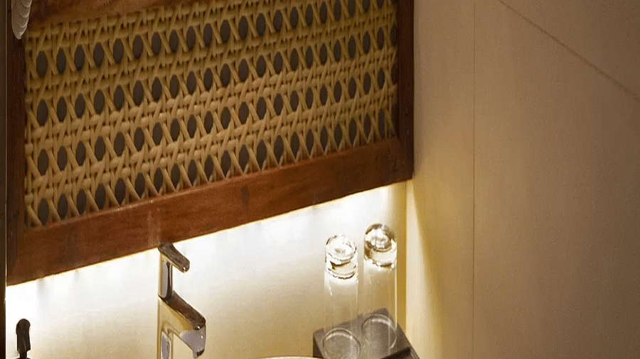 Image of bathroom of Coral Sapphire at Coral Reef Resort and Spa in Havelock in dim lighting featuring a sink and a mirror over it with its background lit up with warm lights 