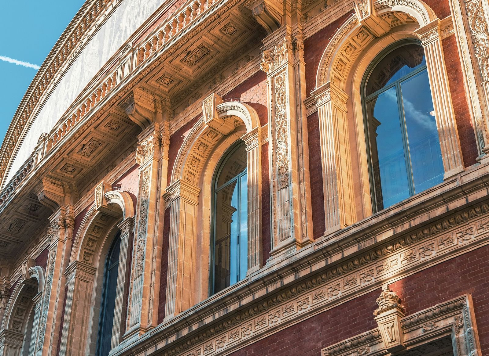 Low-angle view of the Royal Albert Hall facade, showcasing its distinctive red and beige stonework.