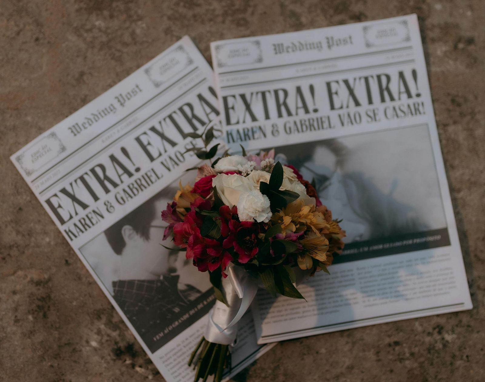 A newspaper with a bouquet of flowers resting on a concrete surface.