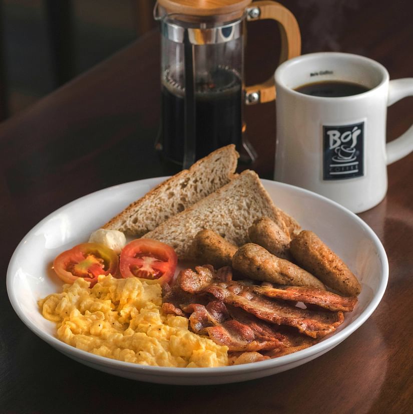 a plate with breakfast items and a coffee mug kept next to it on a table