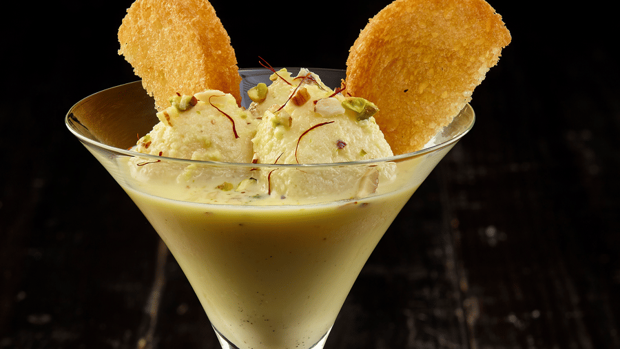 A pistachio kulfi scoops with saffron strands and crisp wafers served in a martini glass at The Citrine, Bangalore.