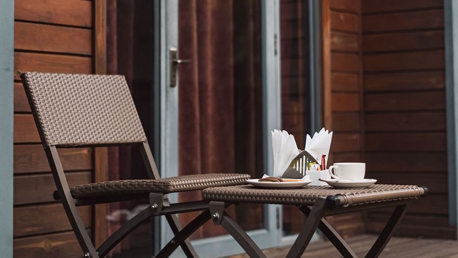 Side view of the cottage at Crescent Spa & Resort, Indore, with a table and chair placed outside, and napkins neatly arranged on the stand on the table
