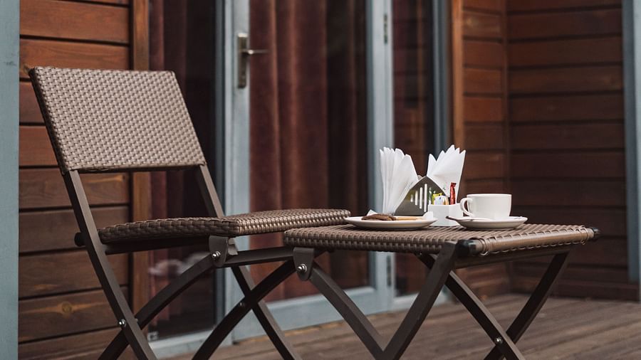 Side view of the cottage at Crescent Spa & Resort, Indore, with a table and chair placed outside, and napkins neatly arranged on the stand on the table