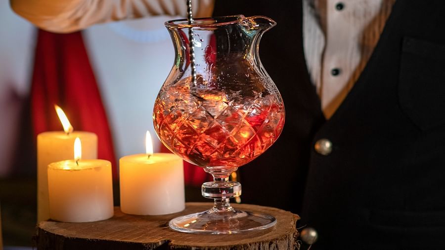  image of a bartender at the aura bar creating a cocktail on a wooden log - The Claridges New Delhi