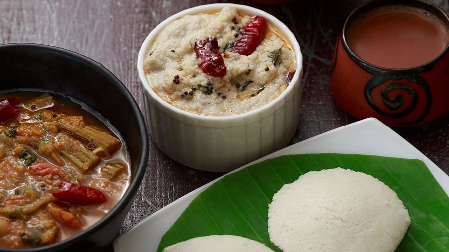 A top-down view of a plate with South Indian food, including what appears to be idli, sambar, and chutney.