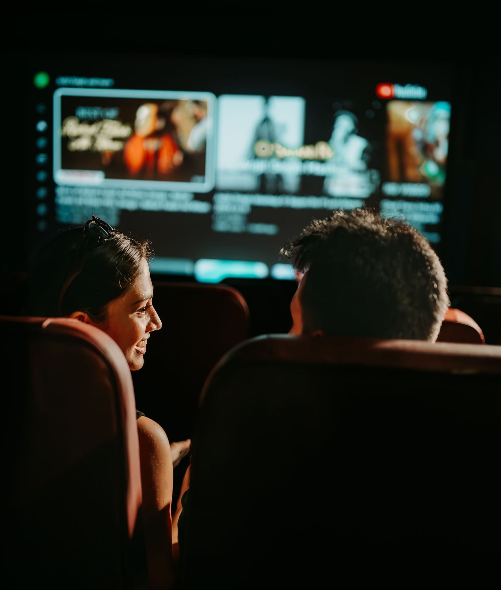 An over-the-shoulder view of a couple having fun and enjoying their movie time in the mini theatre at Crescent Spa & Resort, Indore