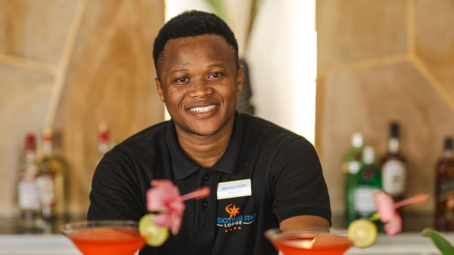 View of a man placing drinks on a table at Shooting Star boutique hotel.