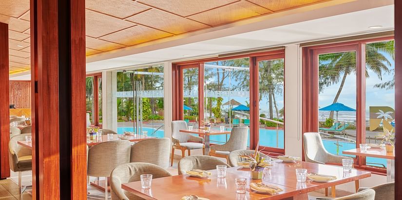 Chairs and tables placed right beside a glass window in a restaurant | The Resort