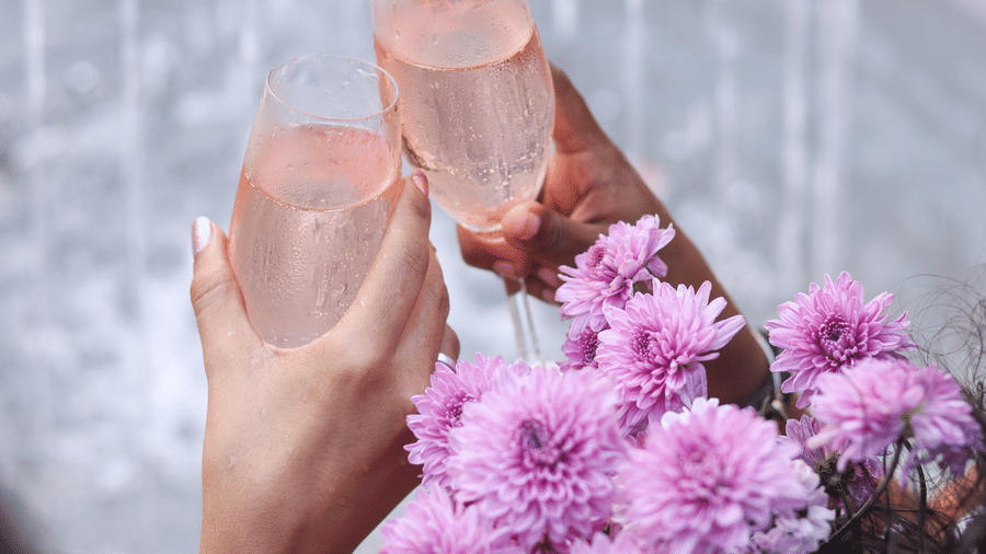 two people clinking glasses of Rosé while holding flowers at Rosé