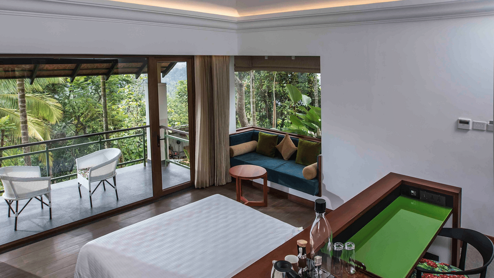 A portrait image of hotel room in Wayanad with cosy furniture and large bed - GReaT trails Wayanad by GRT Hotels