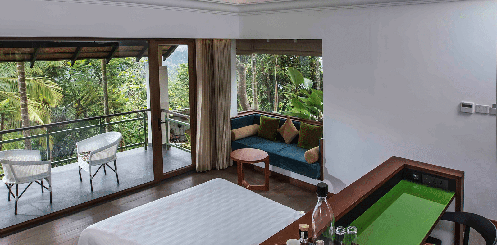 A portrait image of hotel room in Wayanad with cosy furniture and large bed - GReaT trails Wayanad by GRT Hotels
