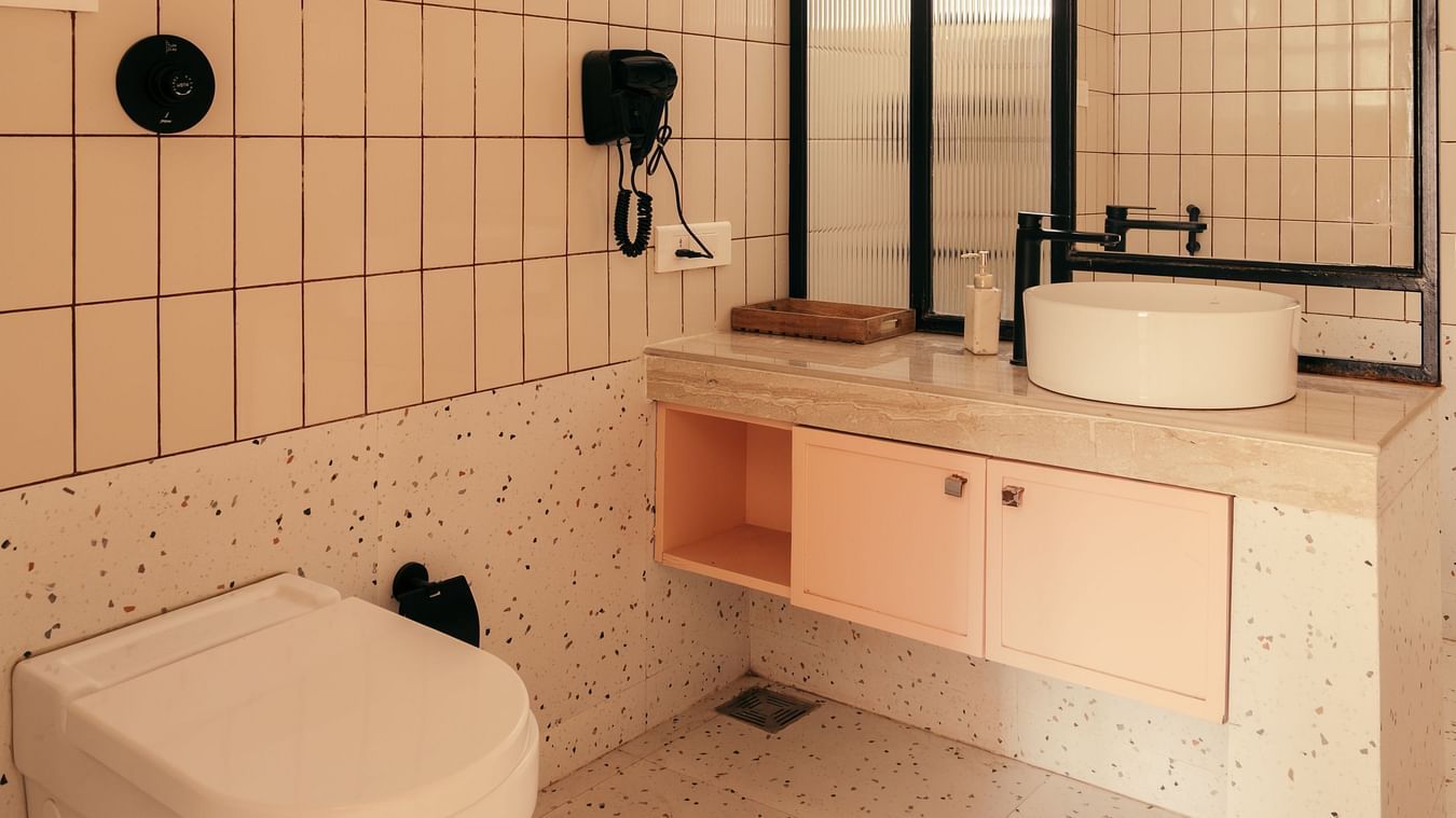 Modern bathroom with beige tiles and black fixtures at Three BHK Premium Villa, Richmonde Ananta Elite, Goa.