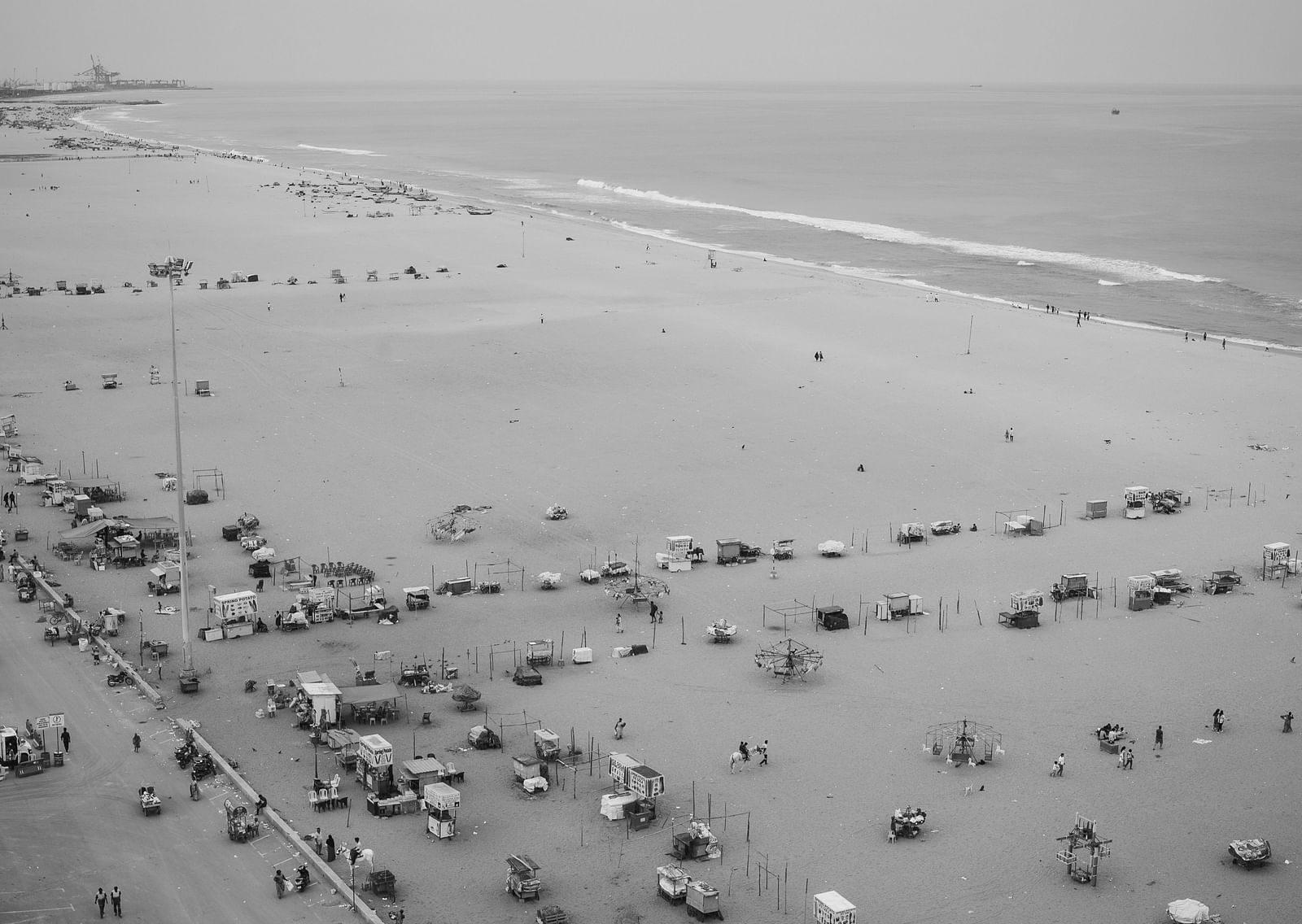An aerial black and white image of Marina Beach with food stalls and people walking in view.