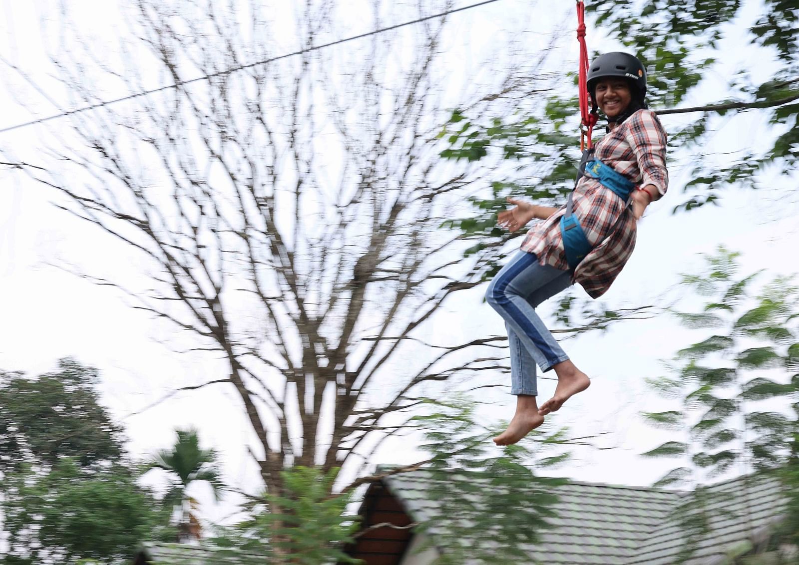 Image of a girl doing zip lining at the hotel | Great Trails Wayanad by  GRT hotels.