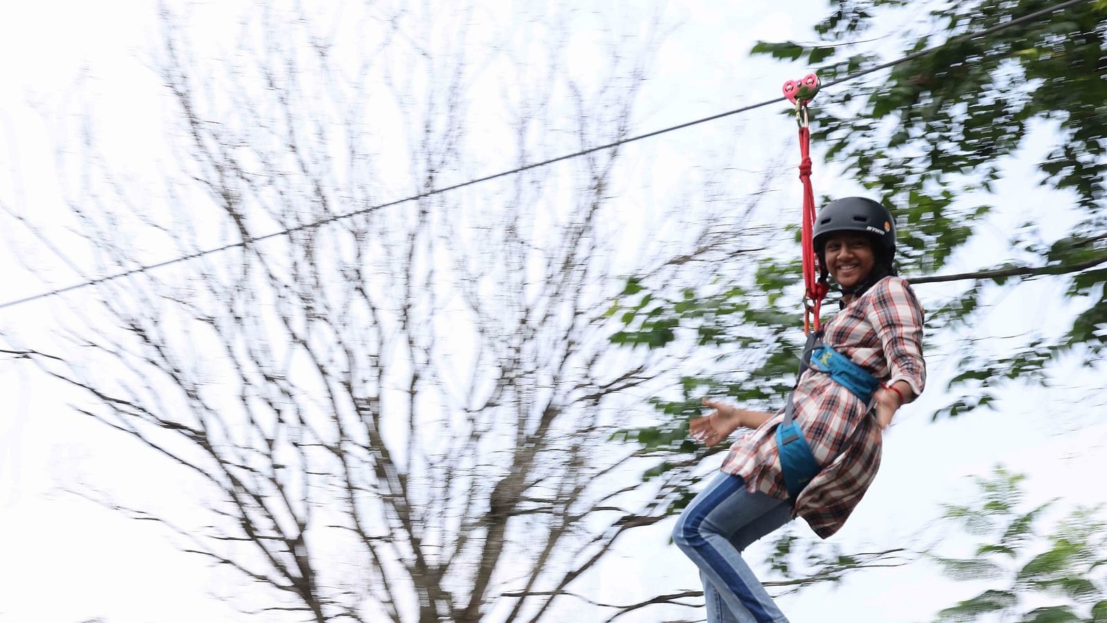Image of a girl doing zip lining at the hotel | Great Trails Wayanad by  GRT hotels.